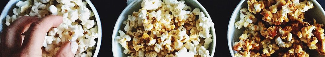 Hand Grabbing Popcorn From Three Tubs