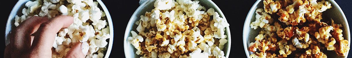 Hand Grabbing Popcorn From Three Tubs